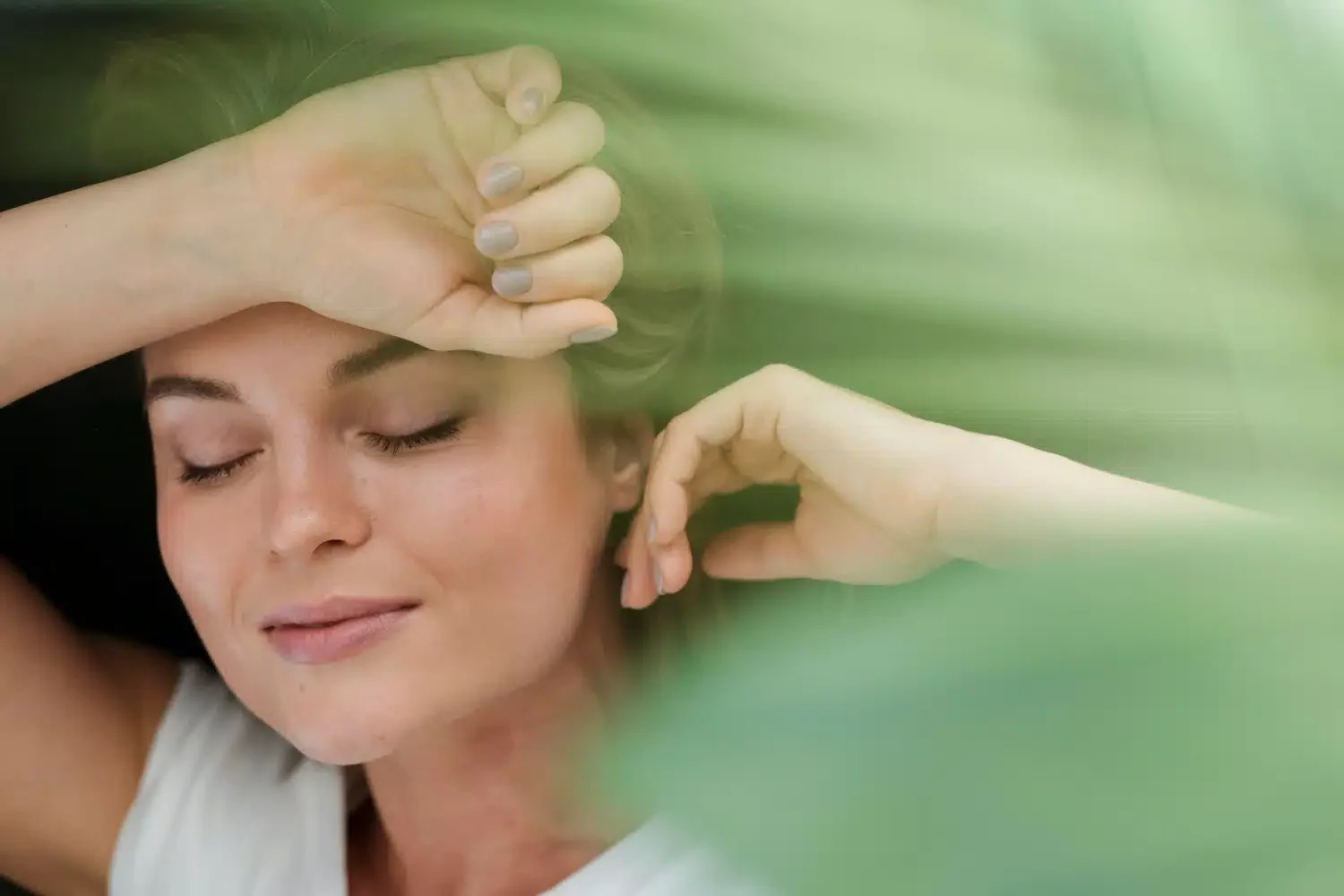 Femme allongée les yeux fermés profitant d’un moment de détente près de plantes vertes